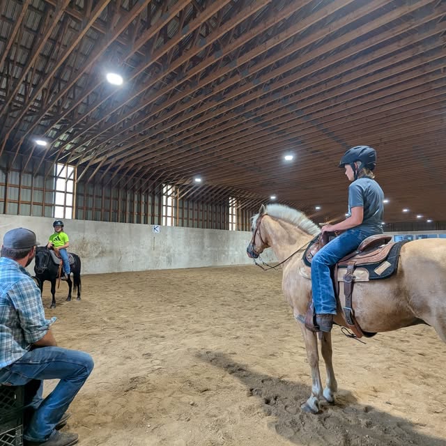 Instructor and student on horseback in arena